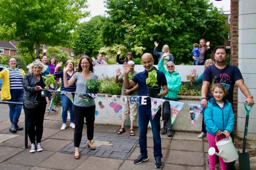 Residents by planter with welcome sign