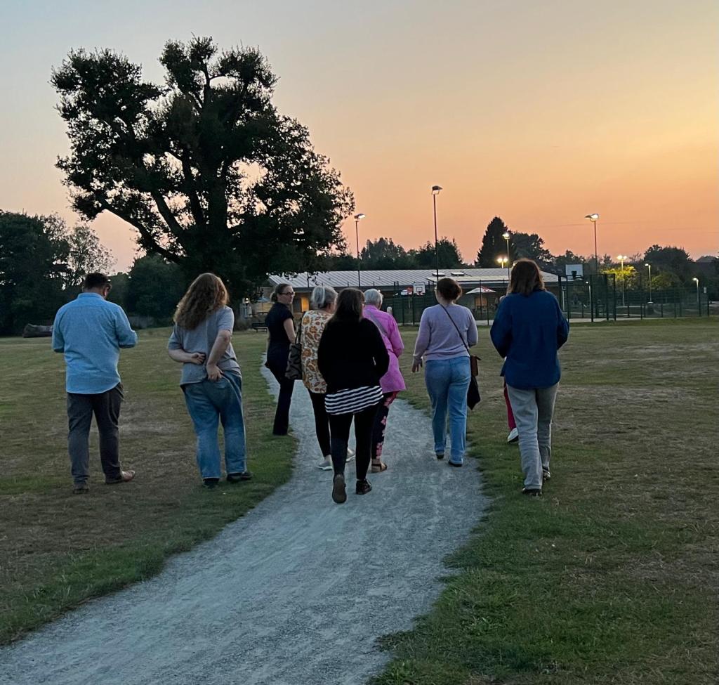 Group of people walking towards building at sunset