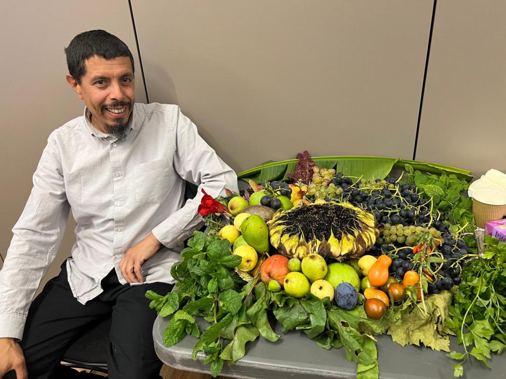 Man next to a platter of fruit, veg and herbs.